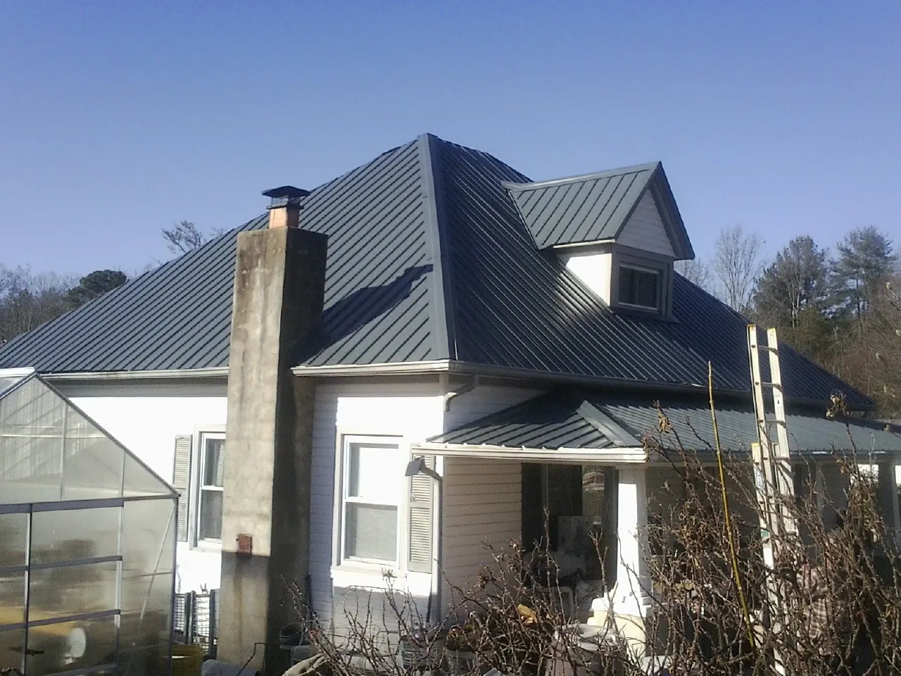 Dark blue standing seam metal roof on a white farmhouse with dormer — Slate & Tile Roof Repair by Roofing Brothers in Walnut