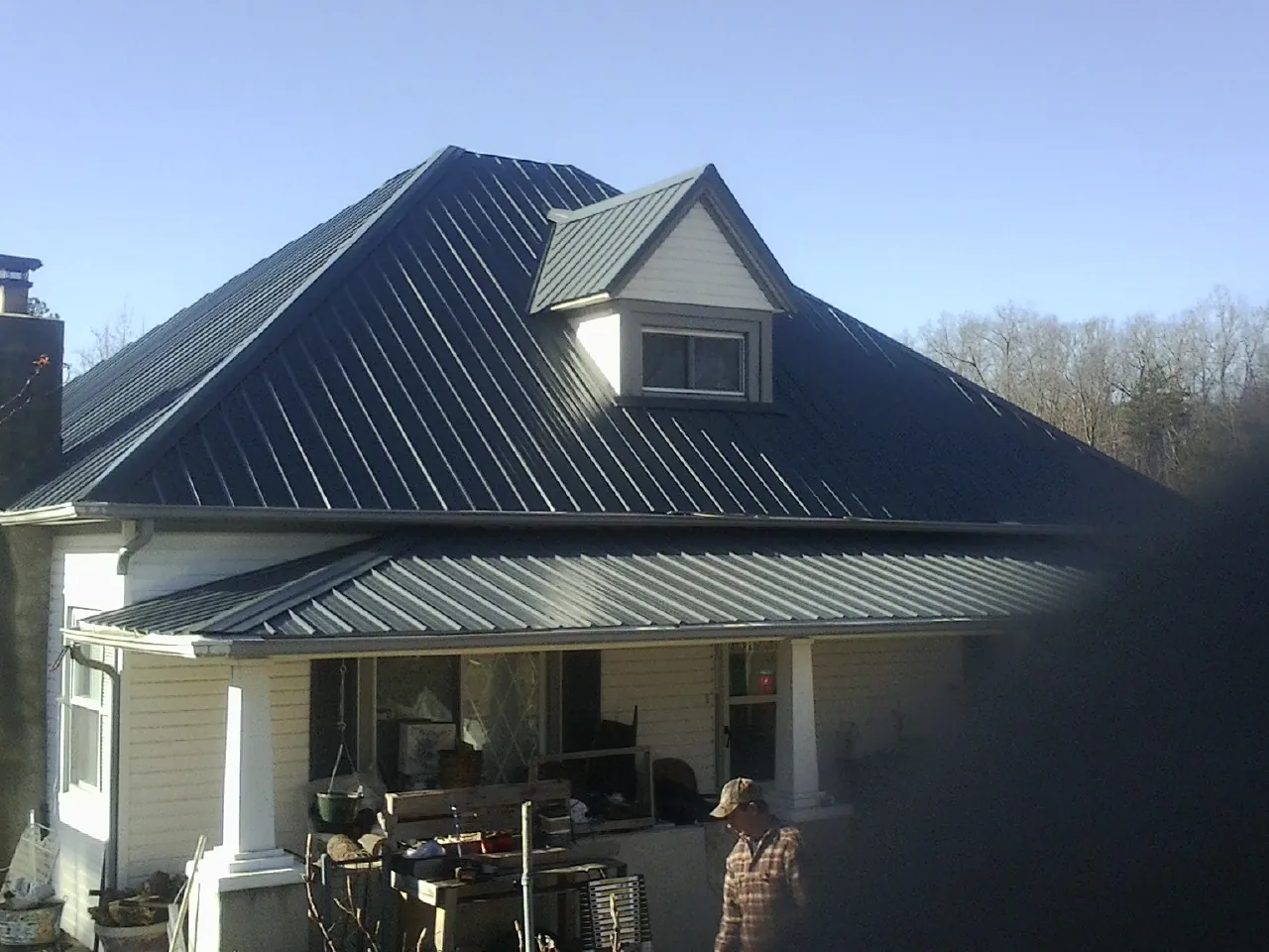 Dark blue standing seam metal roof with a dormer above a front porch in Walnut