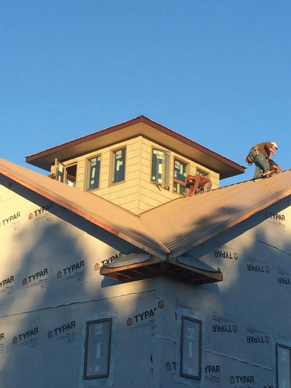 Roofers working around a rooftop cupola on a new metal roof at sunset — Roof Waterproofing in Walnut by Roofing Brothers